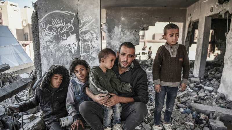 Palestinian Mahmoud Abu Dorra, who lost his wife during the Israeli attacks, is seen with his 4 children among the rubbles of a ruined building (Image: Anadolu via Getty Images)