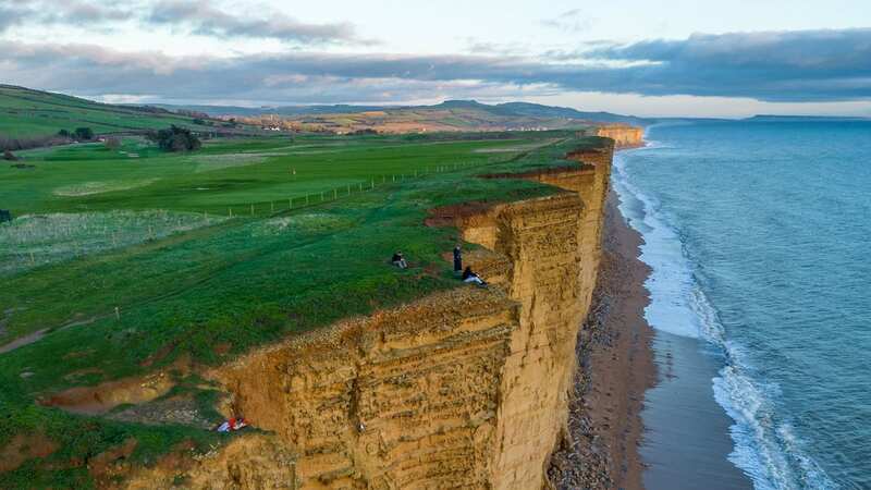 People were spotted near the edge of a cliff at West Bay near Bridport, Dorset (Image: SWNS)