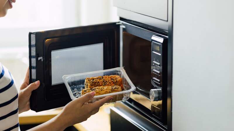 A woman reheating a meal in a microwave oven (Image: Getty Images)