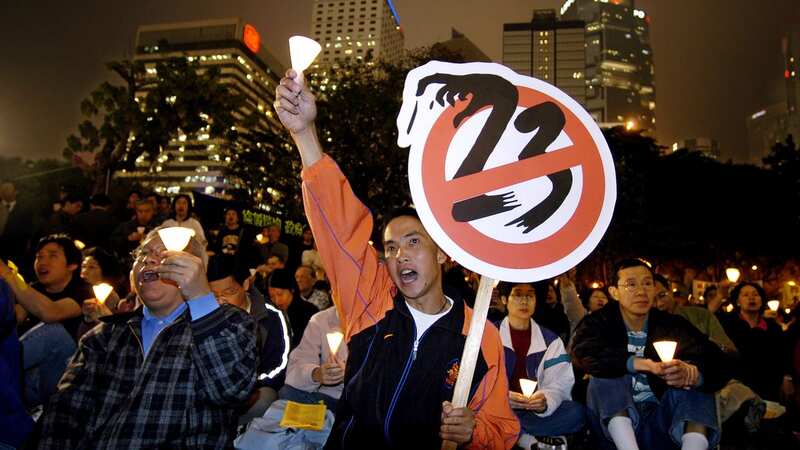 Holding a sign of anti-Article 23 bill, pro-democracy activists shout slogans during a candlelight vigil at a downtown Hong Kong park (Image: Copyright 2022 The Associated Press. All rights reserved.)