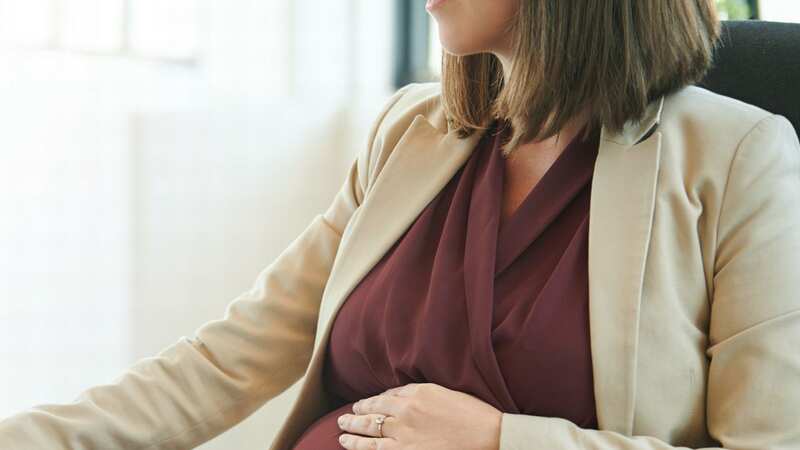 A pregnant woman is pictured working at a des (file image) (Image: Getty Images)