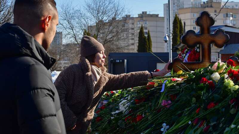 A mourner reaches out to touch the final resting place of Alexei Navalny (Image: AFP via Getty Images)