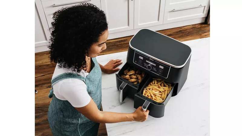 Woman opening a Ninja Foodi Max Dual Zone air fryer with chips in each one (Image: Ninja)