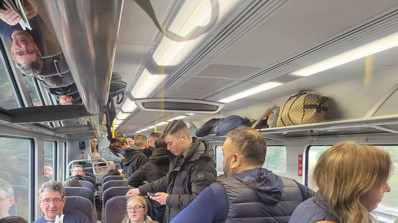 Football fans lying in overhead storage on a train to Birmingham (Image: TJ Jackson/SWNS)