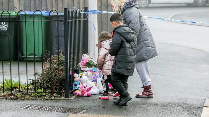 A family leaves tributes at the scene in Rowley Regis, West Midlands (Image: Joseph Walshe / SWNS)