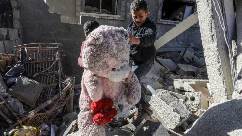 Palestinian children carry teddy bears as gather to inspect damage of the destroyed building, belonged to the al-Fakavi family (Image: Anadolu via Getty Images)