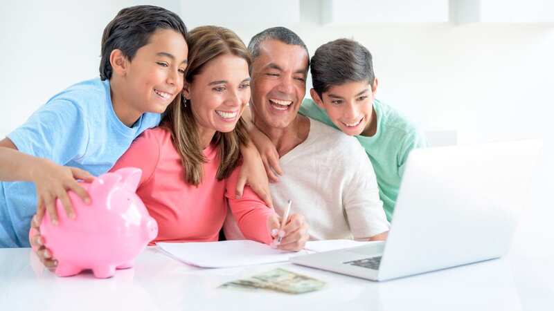 Family saving money in a piggybank while paying bills online (Image: Getty Images)