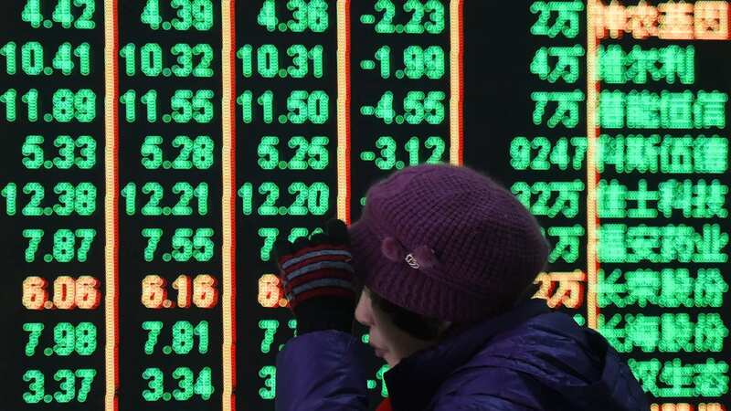 A woman reacts in front of an electronic screen displaying stock prices at a brokerage house in Hangzhou in east China