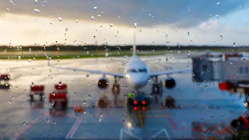 Airfield with passenger aircraft seen through rainy window at Hamburg International Airport, Germany