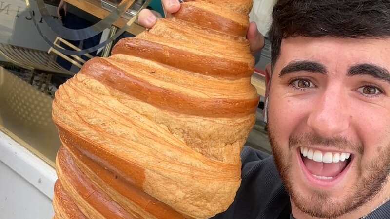 Callum Ryan eating a giant croissant at the Phillipe Contichini café in London (Image: Callum Ryan/SWNS)