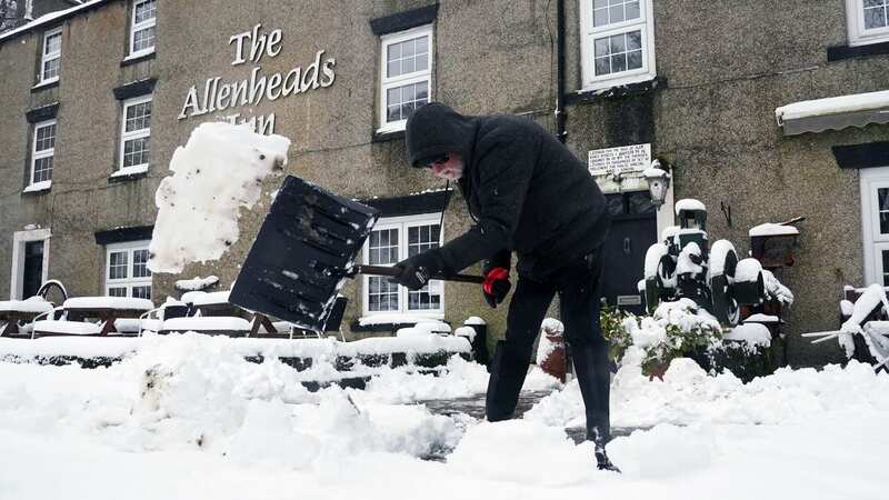 A person clears snow outside The Allenheads Inn in Northumberland as thr North braces for a flurry of the white stuff next week (Image: PA)
