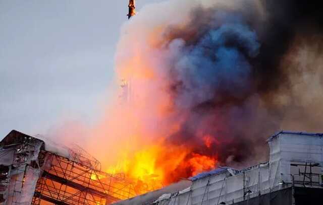 A spire collapses on the historic Børsen building during a fire at the Copenhagen Stock Exchange