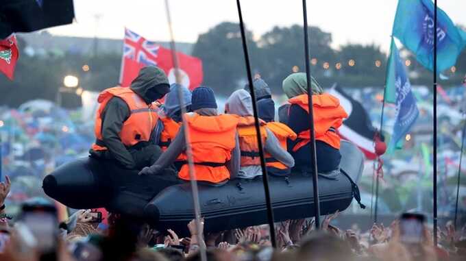 Banksy has claimed credit for a migrant boat artwork displayed in the crowd at Glastonbury