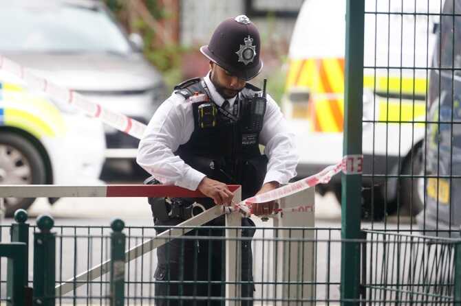 A police officer attaches tape as police search a property in Shepherd’s BushCredit: PA