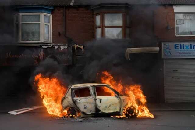 A car burns on Parliament Road after it was set alight by far-right activists (Picture: Getty)