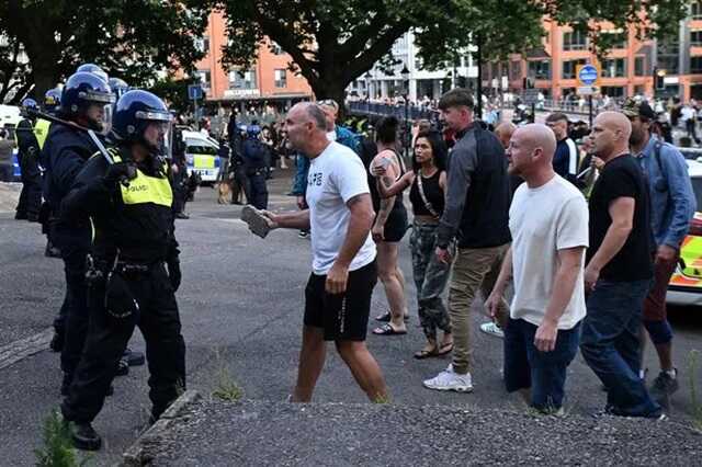 A protester holding a piece of concrete walks towards riot police during a clash in Bristol ( Image: AFP via Getty Images)