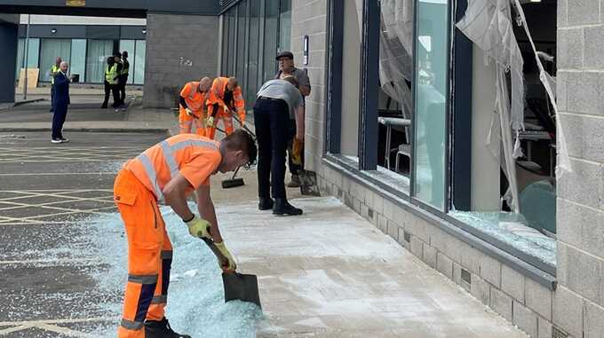 People clear debris outside a Holiday Inn Express in Rotherham. Pic: PA