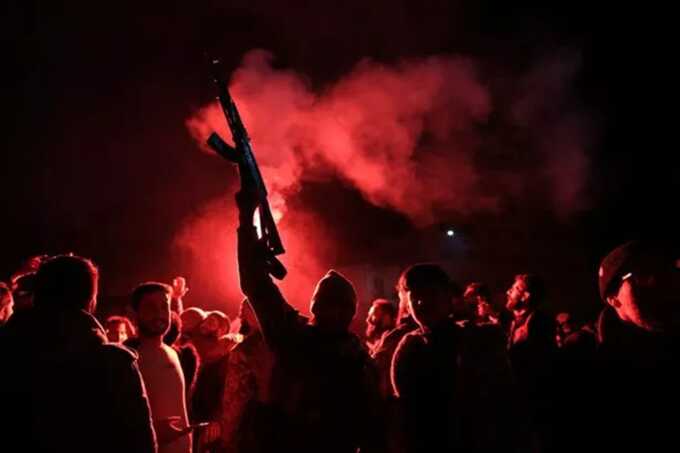 Rebel forces shoot in the air as they celebrate in the central Syrian city of Homs ( Image: AFP via Getty Images)