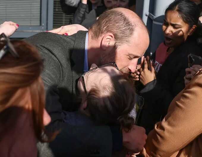 Prince William embraces an astonished fan as he’s surrounded by excited students