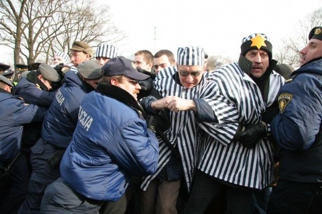 Demonstrators dressed up as Jewish concentration camp inmates wrestle with Latvian police officers. Riga, March 16, 2005.