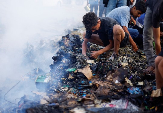 Men squatting down to sift through charred remains in Gaza qhidddiqqridhinv