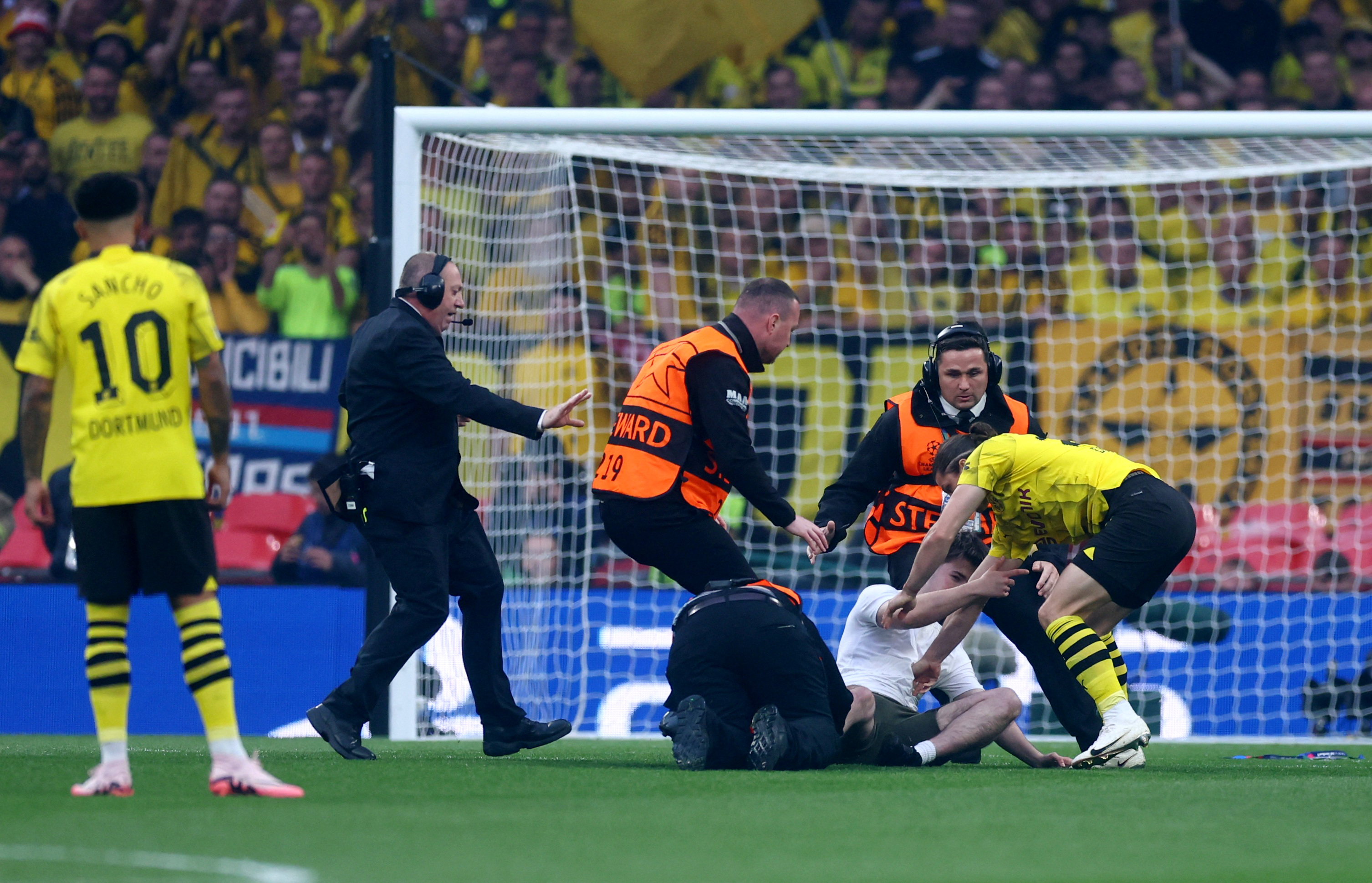 A pitch invader is taken down with the help of Dortmund player Marcel Sabitzer