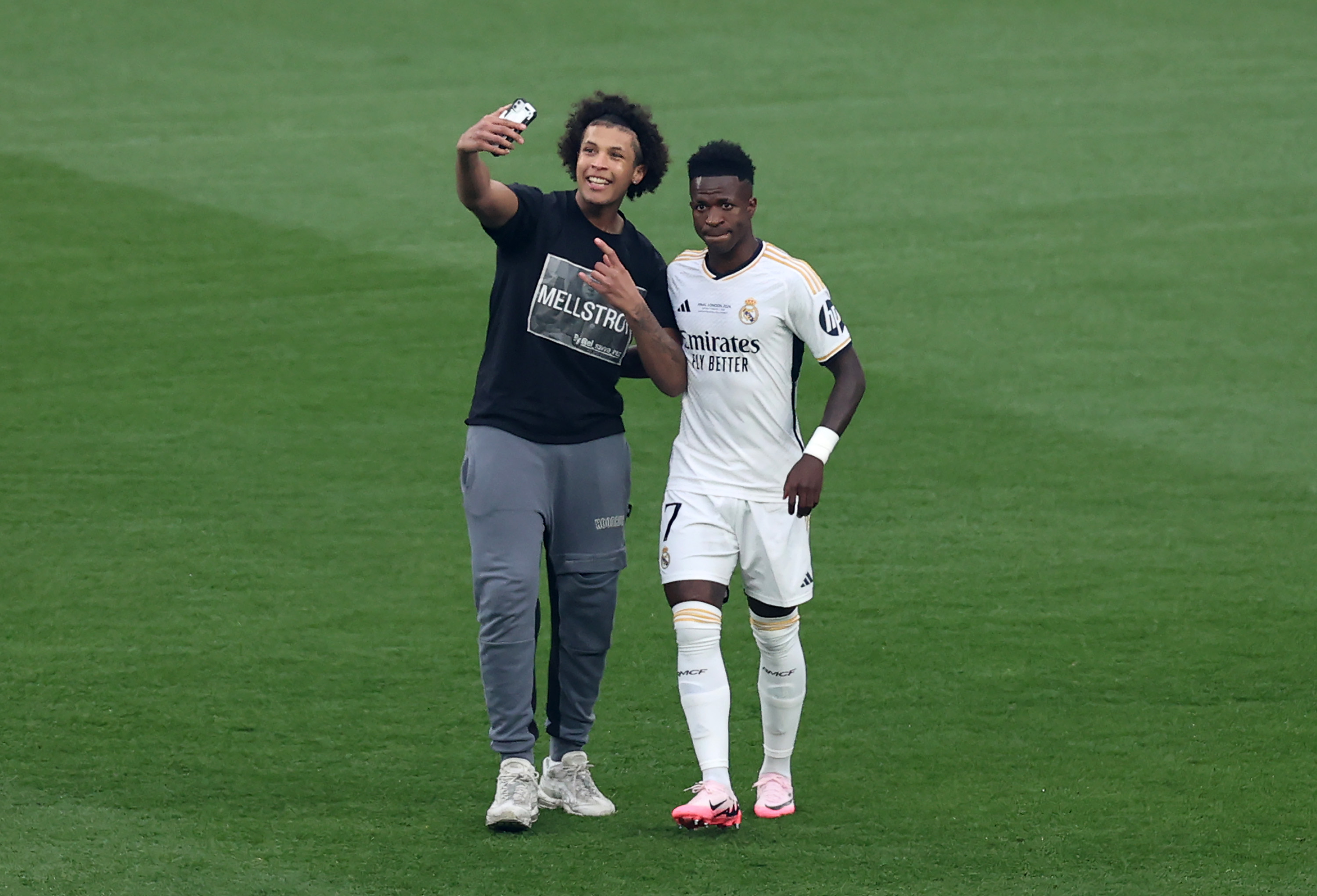 A pitch invader attempts to take a selfie on a mobile phone with Vinicius Jr