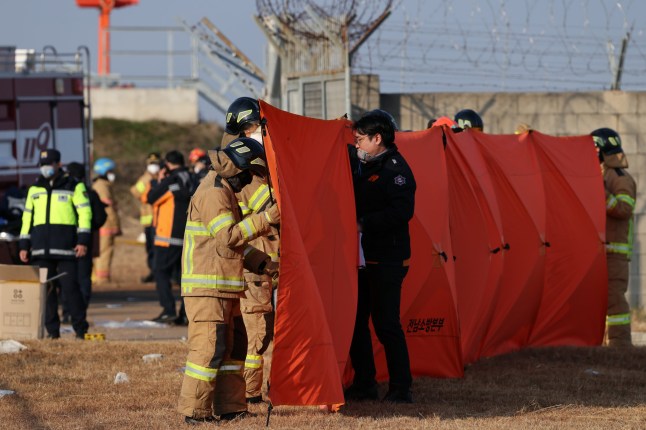 epa11796861 Firefighters deploy a folding screen during rescue operations at Muan International Airport in Muan, 288 kilometers southwest of Seoul, South Korea, 29 December 2024. According to the National Fire Agency, a passenger jet carrying 181 people erupted in flames after going off the runway at an airport in South Korea’s southwestern county of Muan on 29 December, leaving at least 124 people dead. EPA/HAN MYUNG-GU