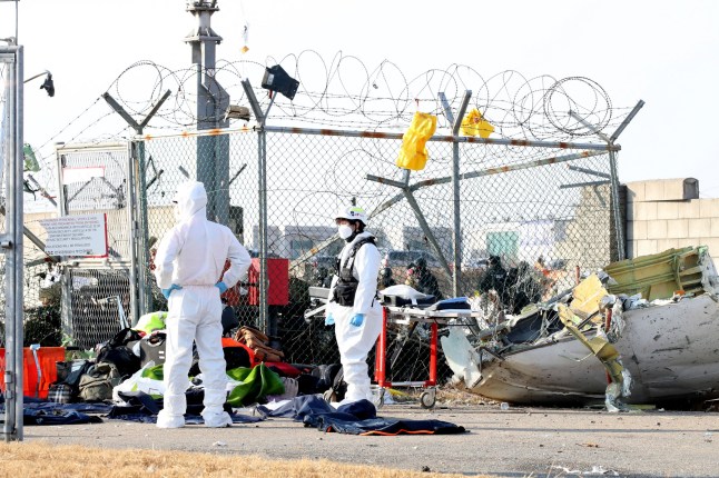 MUAN-GUN, SOUTH KOREA - DECEMBER 29: Firefighters check near the wreckage of a passenger plane at Muan International Airport on December 29, 2024 in Muan-gun, South Korea. A plane carrying 181 people, Jeju Air Flight 7C2216, crashed at Muan International Airport in South Korea after skidding off the runway and colliding with a wall, resulting in an explosion. Early reports said that at least 120 people had died. (Photo by Chung Sung-Jun/Getty Images)