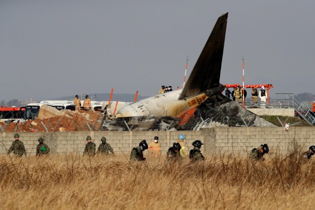 MUAN-GUN, SOUTH KOREA - DECEMBER 29: South Korean soldiers check near the wreckage of a passenger plane at Muan International Airport on December 29, 2024 in Muan-gun, South Korea. A plane carrying 181 people, Jeju Air Flight 7C2216, crashed at Muan International Airport in South Korea after skidding off the runway and colliding with a wall, resulting in an explosion. Early reports said that at least 120 people had died. (Photo by Chung Sung-Jun/Getty Images)