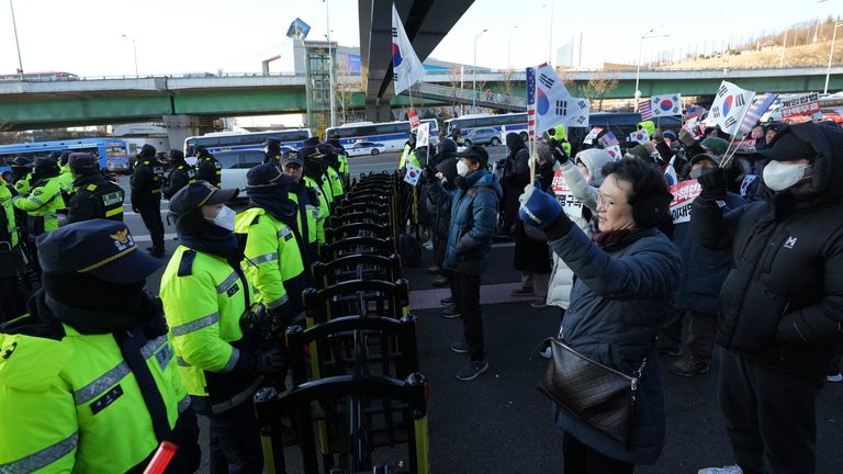 Supporters of impeached South Korean President Yoon Suk Yeol stage a rally to oppose a court having issued a warrant to detain Yoon, as police offices stand guard near the presidential residence in Seoul, South Korea, Friday, Jan. 3, 2025. The letters read "Oppose Impeachment." (AP Photo/Lee Jin-man) eiqekidzziqeuinv