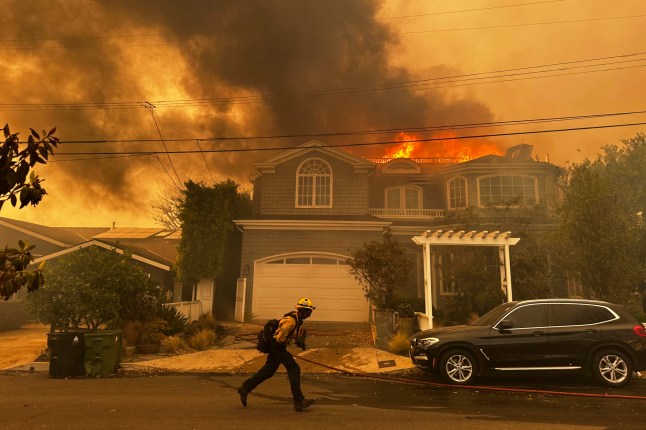 A residence burns as a firefighter battles the Palisades Fire in the Pacific Palisades neighborhood of Los Angeles Tuesday, Jan. 7, 2025. (AP Photo/Eugene Garcia)