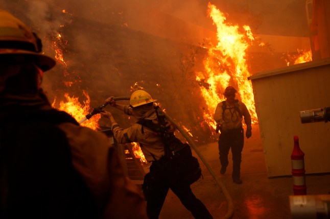 Firefighters protect structures from the advancing Palisades Fire in the Pacific Palisades neighborhood of Los Angeles, Tuesday, Jan. 7, 2025. (AP Photo/Etienne Laurent)