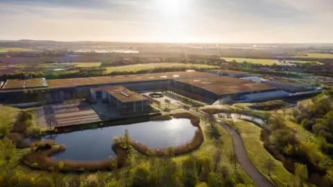 Rolls-Royce Motor Cars An aerial view of Rolls-Royce’s Goodwood site in West Sussex with a sunburst and reflection on its lake