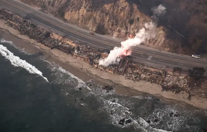 An aerial view of destroyed homes along the beach as the Palisades Fire continues to burn