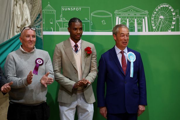 A photograph of Reform UK leader Nigel Farage (far right) with Labour Party candidate Jovan Owusu-Nepaul (centre) on the General Election night