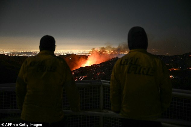 Firefighters watch as the Palisades fire grows near the Mandeville Canyon neighborhood and Encino, California