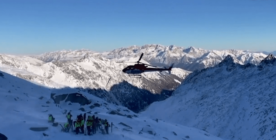 Helicopter over snowy mountains and rescue team. eiqrtihuiqhqinv