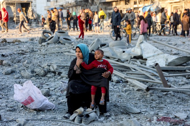 A woman sits with a child with salvaged footwear amidst debris and rubble at the site of Israeli bombardment on a residential block in Jalaa Street in Gaza City on January 14, 2025 amid the ongoing war in the Palestinian territory between Israel and Hamas. (Photo by Omar AL-QATTAA / AFP) (Photo by OMAR AL-QATTAA/AFP via Getty Images)