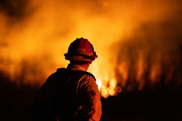 A firefighter monitors the spread of