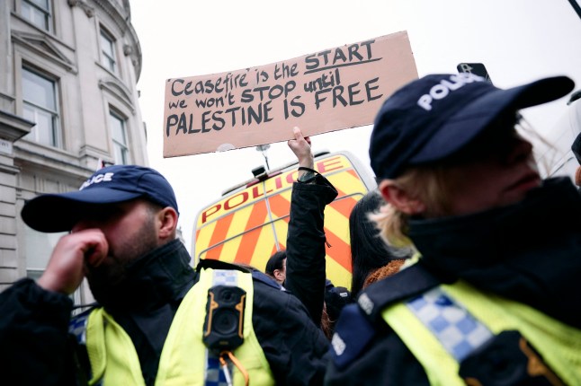 A protester holds up a placard behind the police line on Whitehall in central London at a National demonstration for Palestine, on January 18, 2025, organized by the Palestine Solidarity Campaign. Following the Metropolitan Police preventing a march from the BBC in London because the route passed a synagogue, protesters supporting 