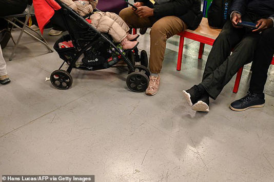 A small child is seen in a buggy as people seek shelter in the theatre