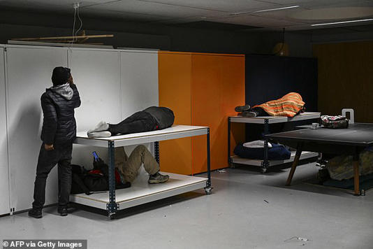 People sleep under a table, on pieces of furniture and charge cellphones during an occupation action in the Gaite Lyrique theatre