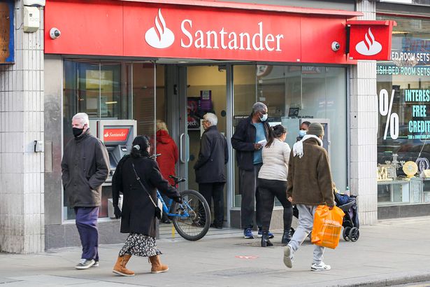 People walk past a branch of Santander Bank.