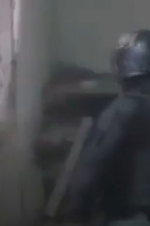 Armoured policeman tries to knock down wall with sledgehammer