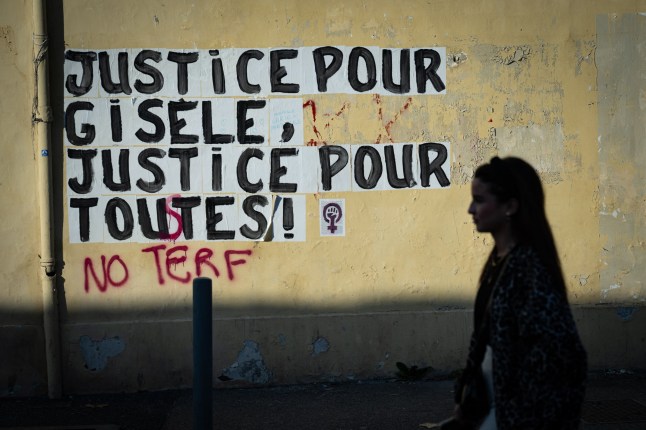 TOPSHOT - A pedestrian walks past a collage mural reading "Justice for Gisele, Justice for all" near the Avignon courthouse, where the Mazan rape trial takes place, in Avignon, southern France on December 18, 2024. Dominique Pelicot, 72, has been on trial since September for masterminding the mass rapes of his wife Gisele Pelicot by strangers who responded to his online invitation to visit the family home in Mazan, southern France. The verdict is expected on December 19, 2024 for Pelicot, who faces 20 years in jail after admitting the charges, and 50 other men are to be sentenced this week after a trial that has shocked France. (Photo by MIGUEL MEDINA / AFP) (Photo by MIGUEL MEDINA/AFP via Getty Images) eiqrtiqzeiqdinv