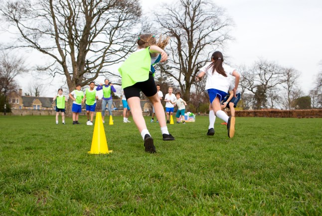 FDAA19 School children wearing sports uniform running around cones during a physical education session. qhiqhuiqhhiqdqinv