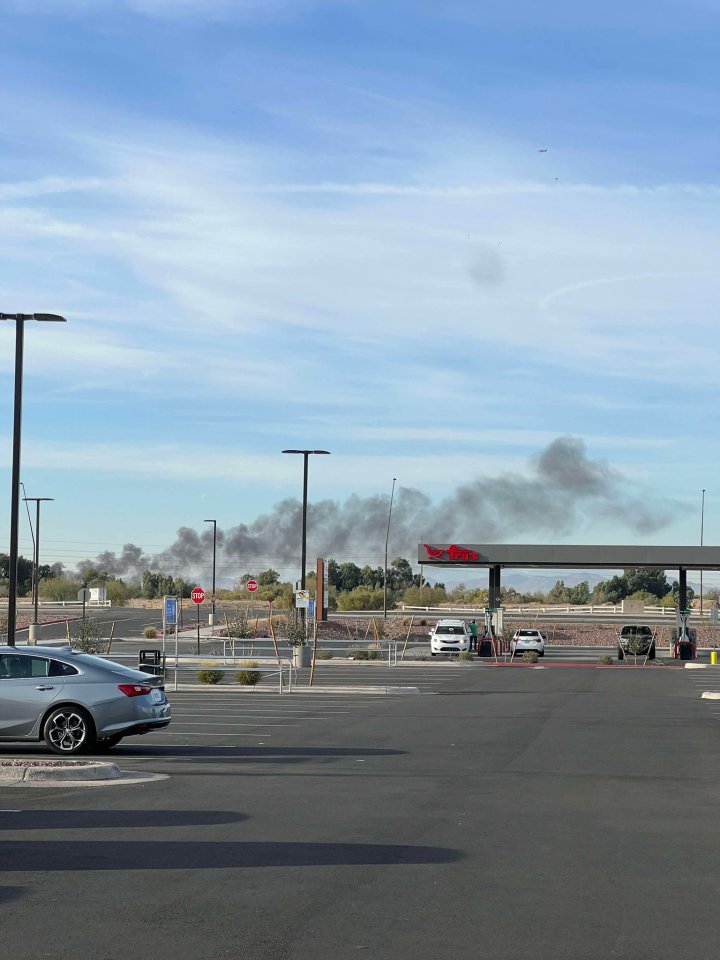 Large plume of black smoke in the distance, visible from a parking lot. tidttiqzqiqkdinv qhidddidqhidhprw