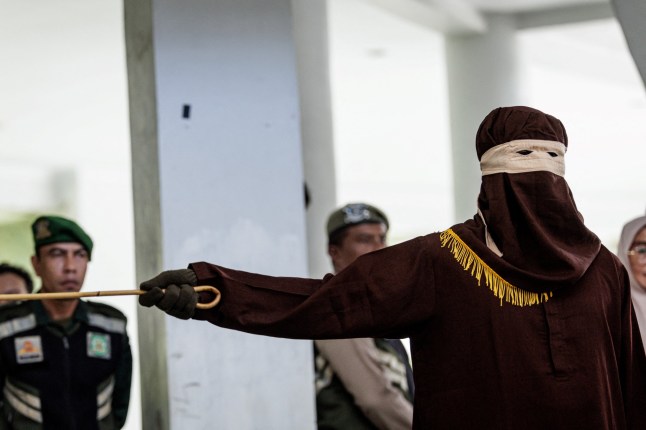 A member of the Sharia police flogs a man found guilty of sexual relations with another man under the strict Islamic sharia law, in Banda Aceh on February 27, 2025. (Photo by YASUYOSHI CHIBA / AFP) (Photo by YASUYOSHI CHIBA/AFP via Getty Images) qhiddqiqrtiquhinv