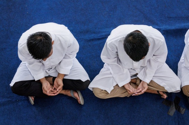 Two men, found guilty of sexual relations with another man under the strict Islamic sharia law, listen to the words of an ustaz, an Islamic religious teacher, before being publicly flogged in Banda Aceh on February 27, 2025. (Photo by YASUYOSHI CHIBA / AFP) (Photo by YASUYOSHI CHIBA/AFP via Getty Images)